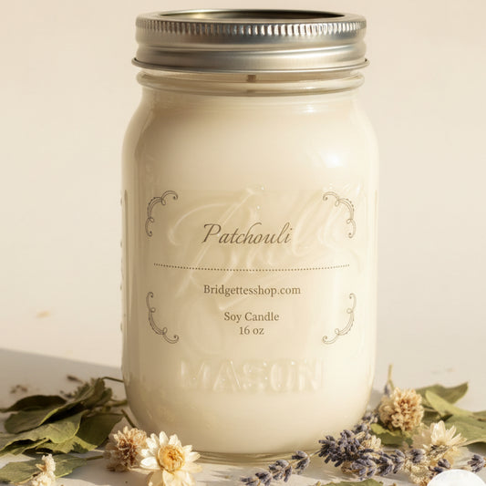White candle in a mason jar with 'Patchouli' branding on a wooden surface