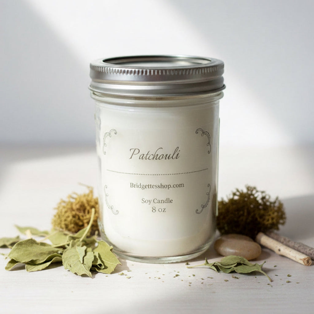 Patchouli soy candle in a glass jar with a silver lid on a light background