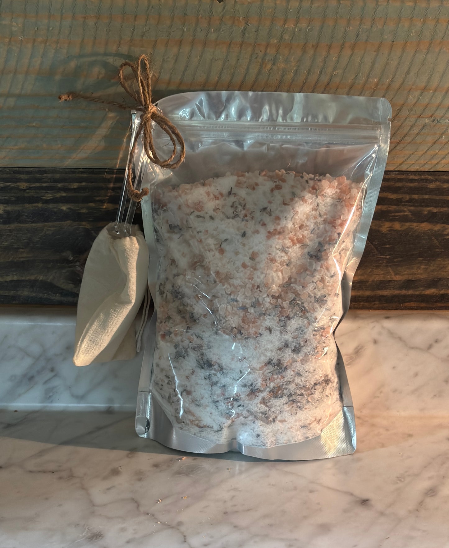 Bag of bath salts with a small scoop on a marble surface