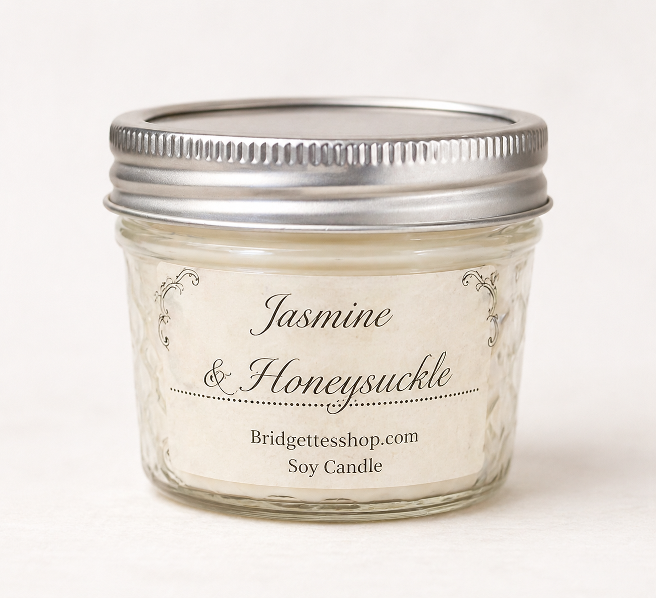 Jar of Jasmine & Honeysuckle candle with silver lid on a white background